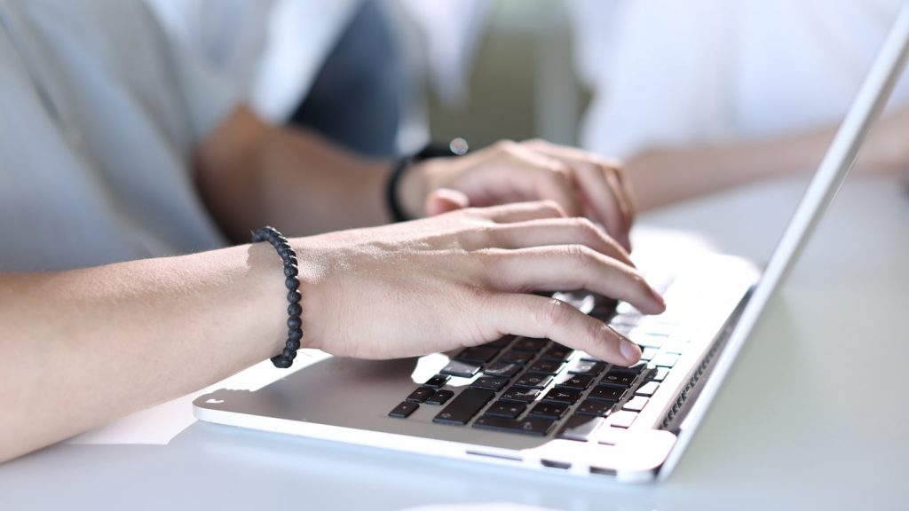 A person typing on a laptop on a table