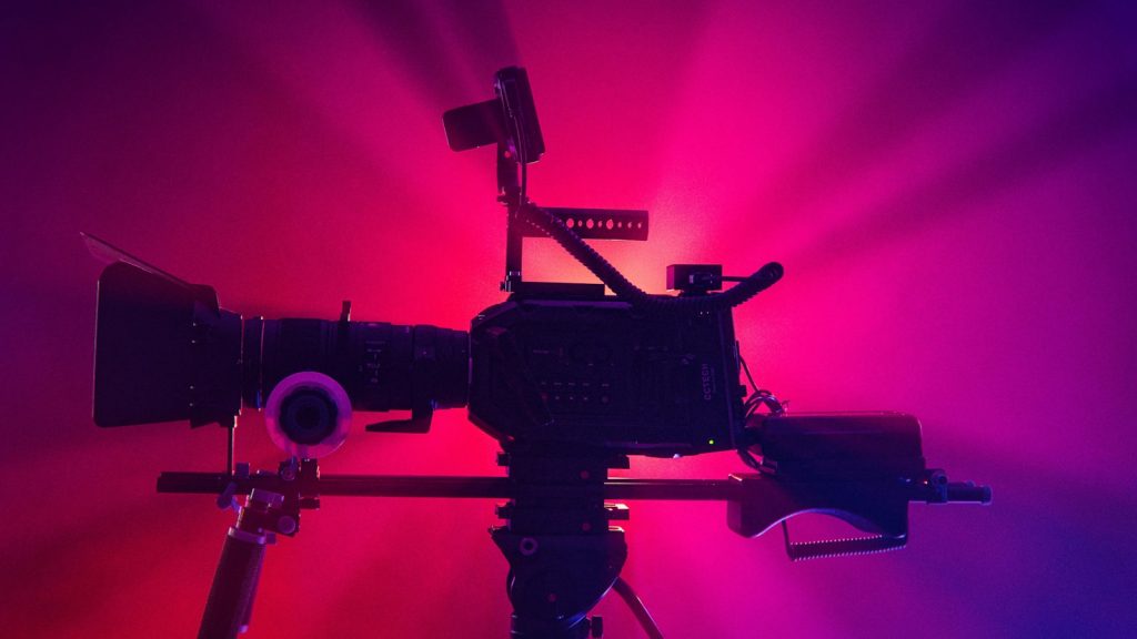 a camera on a tripod in front of a red and purple background