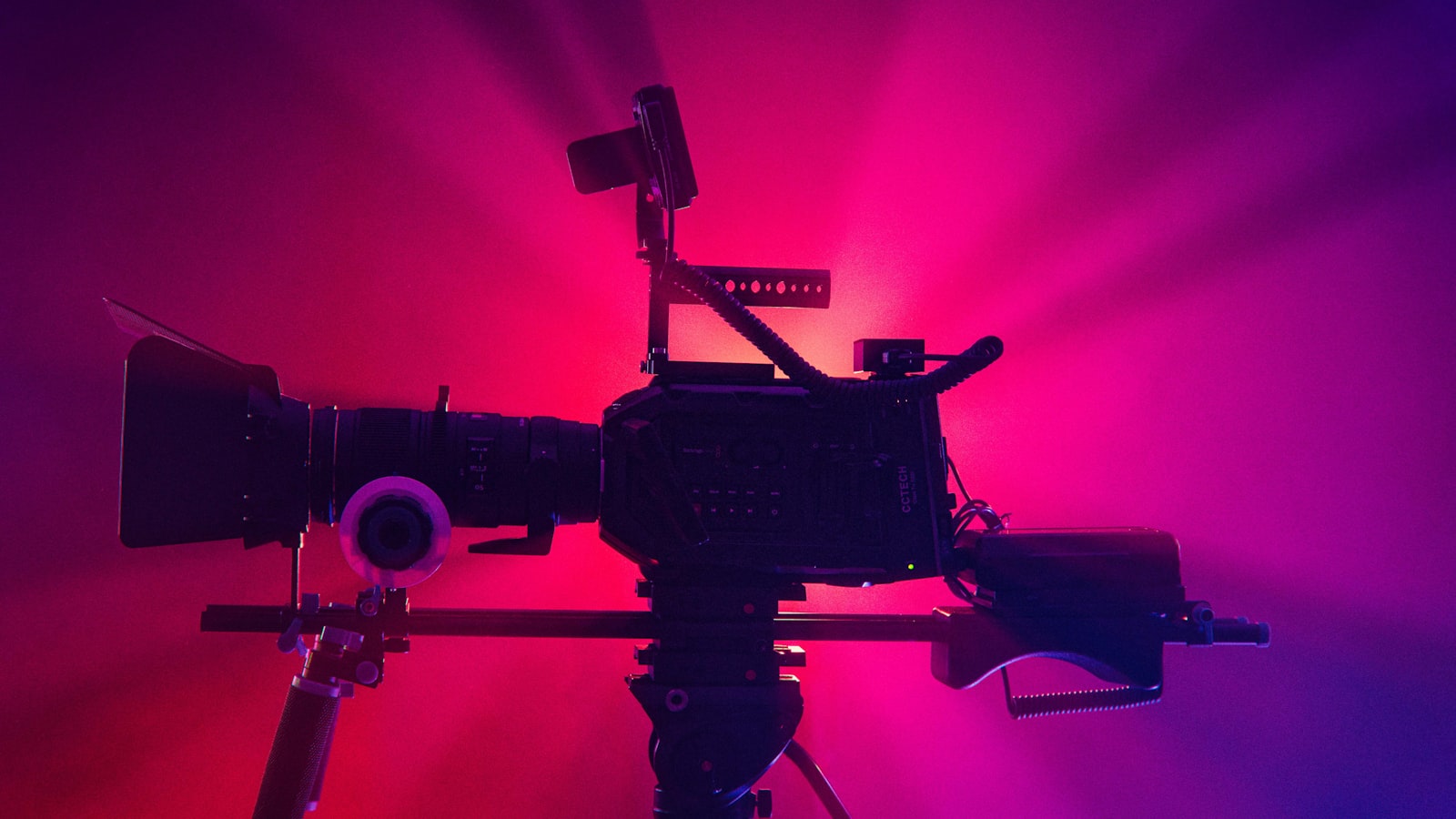 a camera on a tripod in front of a red and purple background